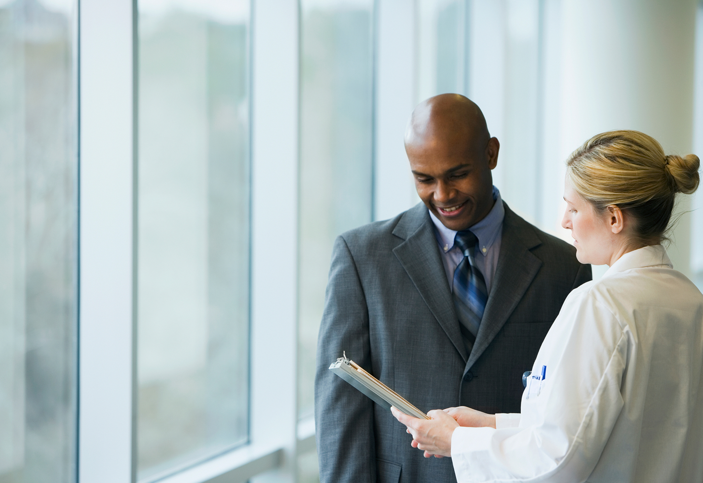 A man in a suit talking with a female provider near a window.
